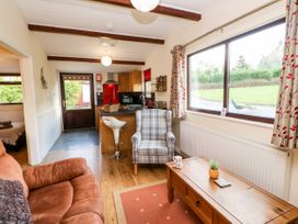 A living room with a brown sofa a plaid armchair a wooden coffee table and a kitchen area at Violet Lodge in Saltburn-by-the-Sea