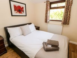 A bedroom with a double bed towels on the bed and a window with patterned curtains at Violet Lodge in Saltburn-by-the-Sea