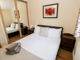 A bedroom with a double bed two bedside tables a framed picture of red flowers and mirrored wardrobe doors at Violet Lodge in Saltburn-by-the-Sea