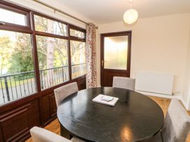 A dining room with a round black table four chairs large windows and a wooden door at Violet Lodge in Saltburn-by-the-Sea