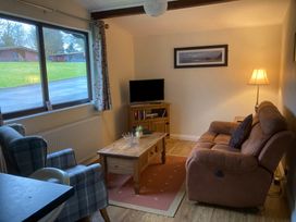 A living room with a sofa, armchair, coffee table, and television at Violet Lodge in Saltburn-by-the-Sea