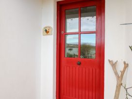 A red door with a welcome sign at Herons Cove Cottage Ballydehop