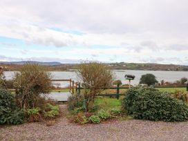 A view of a lake with shrubs and a fence at Herons Cove Cottage Ballydehop