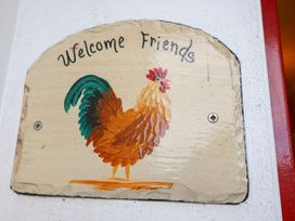 A welcome sign with a rooster design at Herons Cove Cottage in Ballydehop