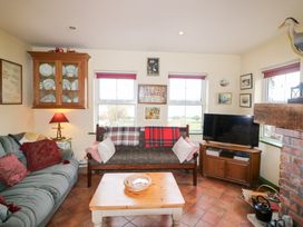 A living room with a sofa and television at Herons Cove Cottage in Ballydehop