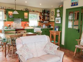 A kitchen with cabinets and a dining table at Herons Cove Cottage in Ballydehop