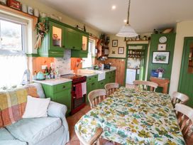 A kitchen with green cabinets and a dining table at Herons Cove Cottage in Ballydehop