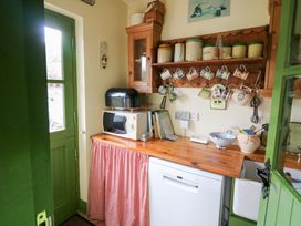 A kitchen with a microwave and mugs on a shelf at Herons Cove Cottage, Ballydehop