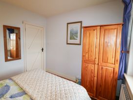 A bedroom with a wardrobe and a mirror at Herons Cove Cottage in Ballydehop