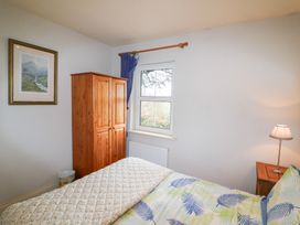 A bedroom with a bed, wardrobe, and window at Herons Cove Cottage in Ballydehop
