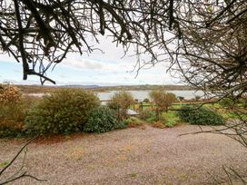 A garden view with plants and water in the distance at Herons Cove Cottage Ballydehop