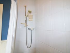 A shower with wall tiles and control valve at Herons Cove Cottage in Ballydehop