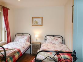 A bedroom with two beds and a bedside table at Herons Cove Cottage in Ballydehop