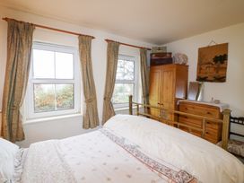 A bedroom with a bed and windows at Herons Cove Cottage Ballydehop