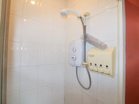 A shower area with a showerhead and control unit at Herons Cove Cottage Ballydehop