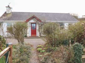 A house with a red door and garden at Herons Cove Cottage, Ballydehop