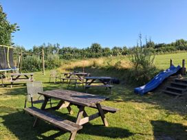 A garden with picnic tables, a trampoline and a slide at Woodstone Barn in Whitchurch near Tavistock