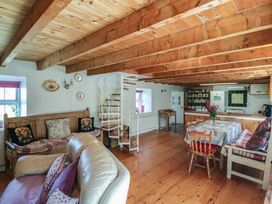 A living room with a sofa, table, and staircase at Fuschia Cottage, Waterville, County Kerry