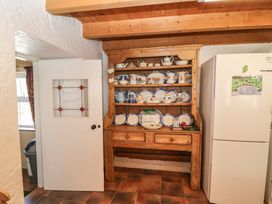 A kitchen with a wooden shelf displaying dishes at Fuschia Cottage Waterville, County Kerry