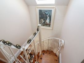 A staircase with a painting and wooden floor at Fuschia Cottage in Waterville, County Kerry