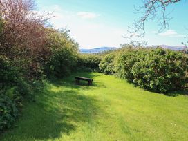 A garden area with a bench surrounded by bushes and grass at Fuschia Cottage in Waterville, County Kerry