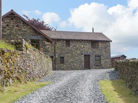 A building with stone walls and a gravel path at Copper Beech Cottage in Torver