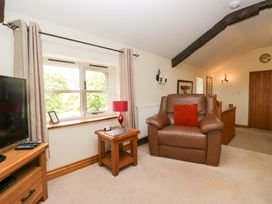 A living room with an armchair and television at Copper Beech Cottage in Torver