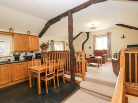 A living room with a kitchen area and dining set at Copper Beech Cottage in Torver