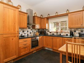 A kitchen with wooden cabinets and appliances at Copper Beech Cottage in Torver