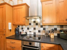 A kitchen with wooden cabinets and an electric stove at Copper Beech Cottage in Torver