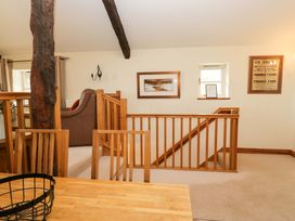 A living room with a sofa and staircase at Copper Beech Cottage in Torver