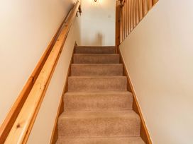 A staircase with carpet and wooden handrail at Copper Beech Cottage Torver
