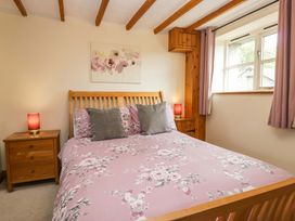 A bedroom with a bed and bedside table at Copper Beech Cottage in Torver
