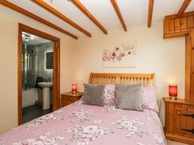 A bedroom with a bed and bathroom access at Copper Beech Cottage in Torver