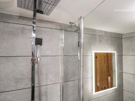 A bathroom with a shower and mirror at Copper Beech Cottage in Torver