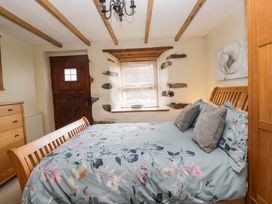 A bedroom with a bed and dresser at Copper Beech Cottage in Torver