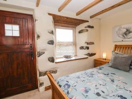 A bedroom with a bed and wooden door at Copper Beech Cottage Torver
