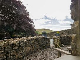 A garden with a stone wall and planter at Copper Beech Cottage Torver