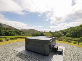 A hot tub on a stone patio with mountains in the background at Copper Beech Cottage in Torver