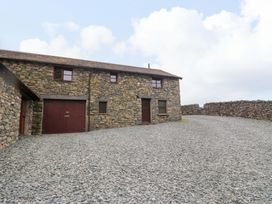 An outdoor view of a stone building with gravel area at Copper Beech Cottage in Torver