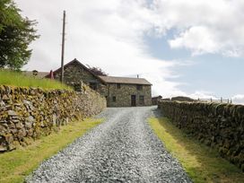 A house with stone walls and gravel drive at Copper Beech Cottage in Torver