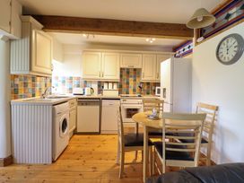 A kitchen with appliances and a dining table at Stabal Cottage in Dolgellau