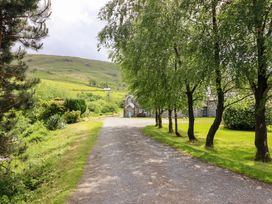 A gravel path lined with trees leading to a building at Stabal Cottage in Dolgellau