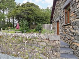 An outdoor area with a stone wall and garden furniture at Yew Tree Cottage Torver
