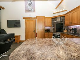 A kitchen with wooden cabinets and appliances at Yew Tree Cottage in Torver