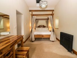 A bedroom with a four-poster bed and dressing table at Yew Tree Cottage in Torver