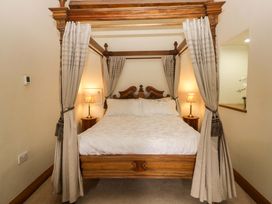 A four-poster bed with bedside lamps at Yew Tree Cottage in Torver
