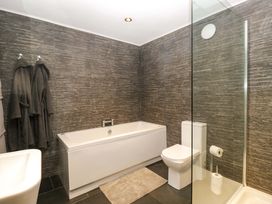 A bathroom with a bathtub, toilet, and shower at Yew Tree Cottage in Torver