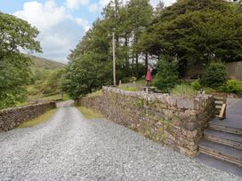 An outdoor area with a gravel pathway and stone wall at Yew Tree Cottage in Torver