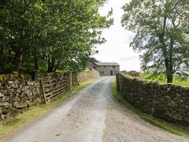 A gravel path leading to a cottage surrounded by trees at Yew Tree Cottage in Torver
